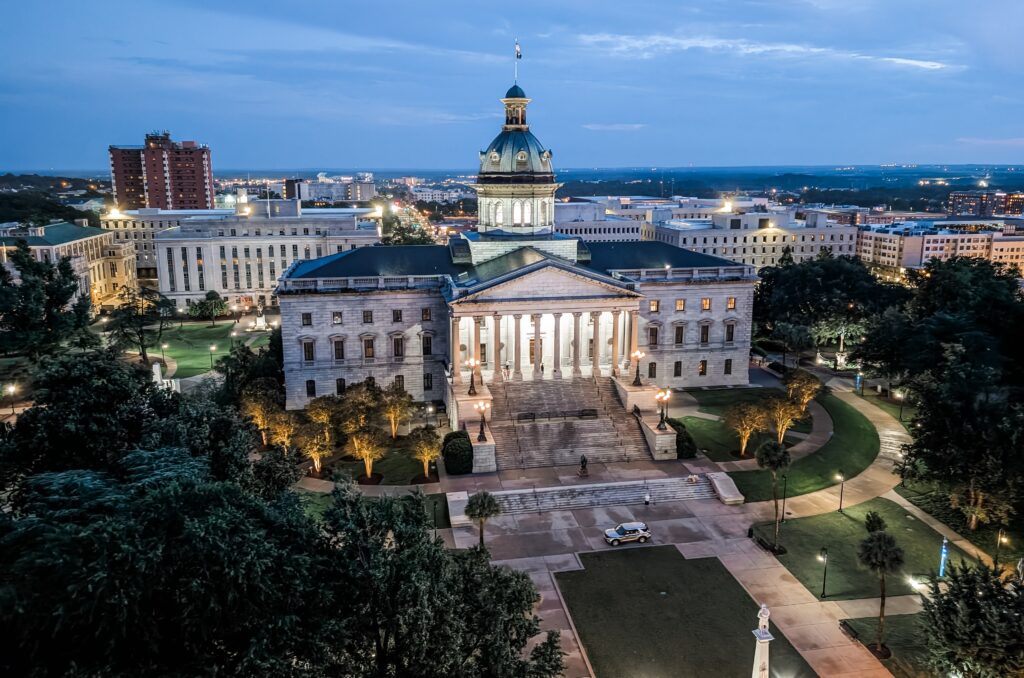 It describes what’s actually visible (Statehouse + skyline), includes your brand and local keywords (Columbia SC, hospitality, vacation rentals), and reads naturally for screen readers.